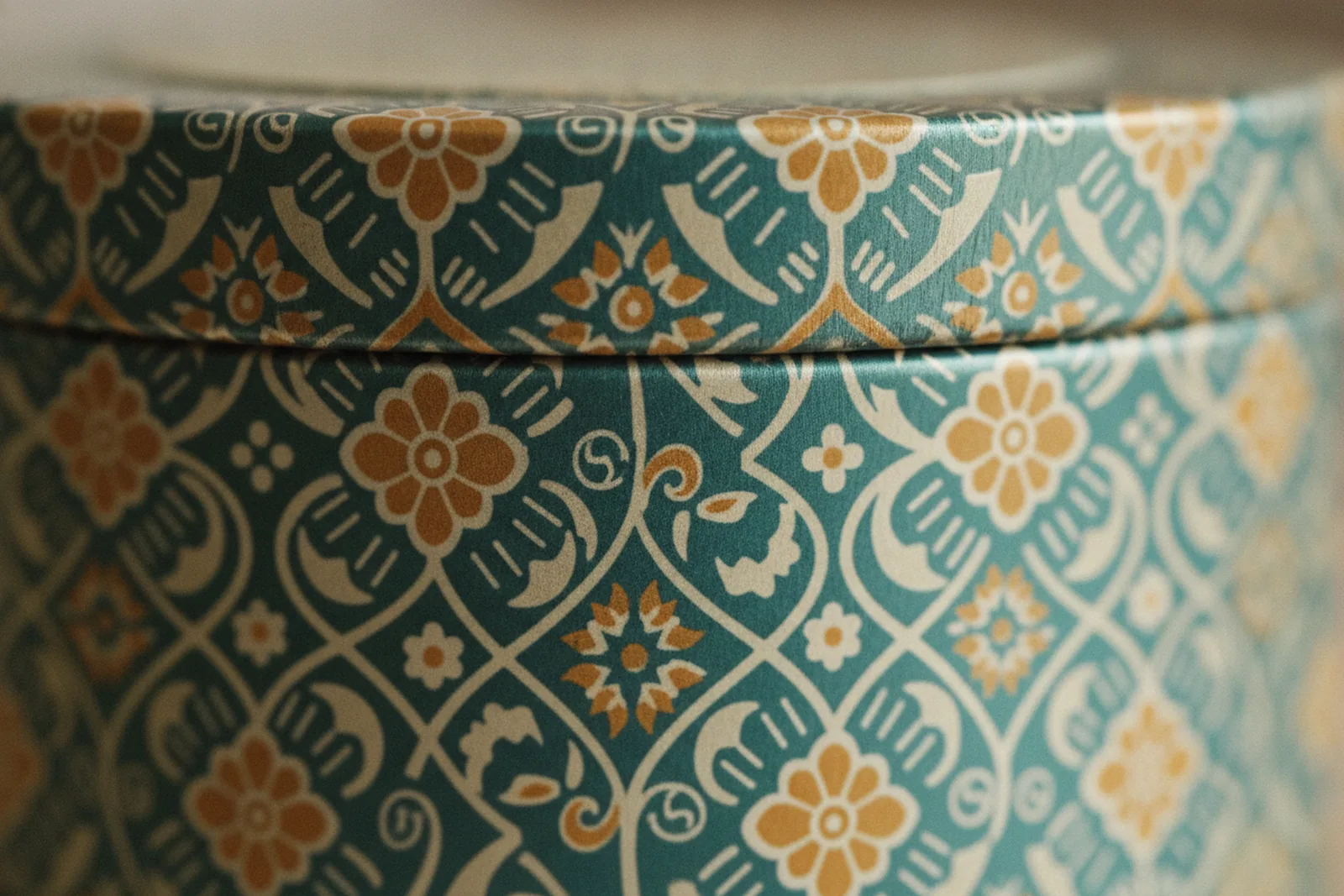 Close-up of a tin showing heritage pattern wrapping continuously around the curved body with no seam