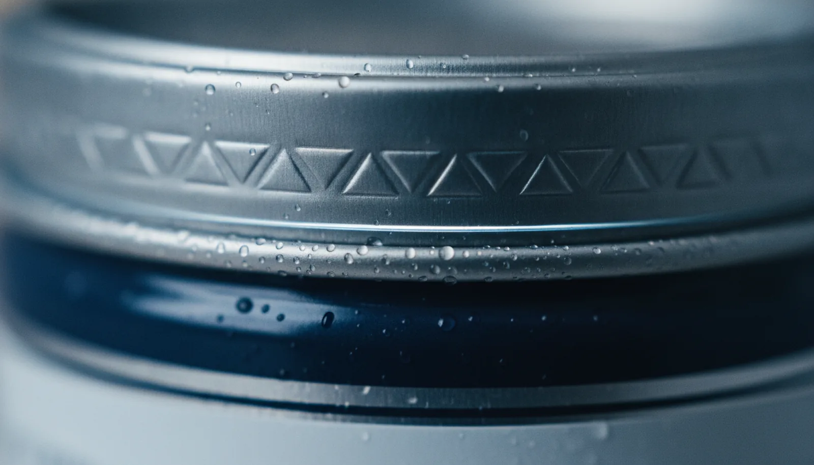 Close-up of a cool metallic tin surface with faint condensation, emphasizing temperature