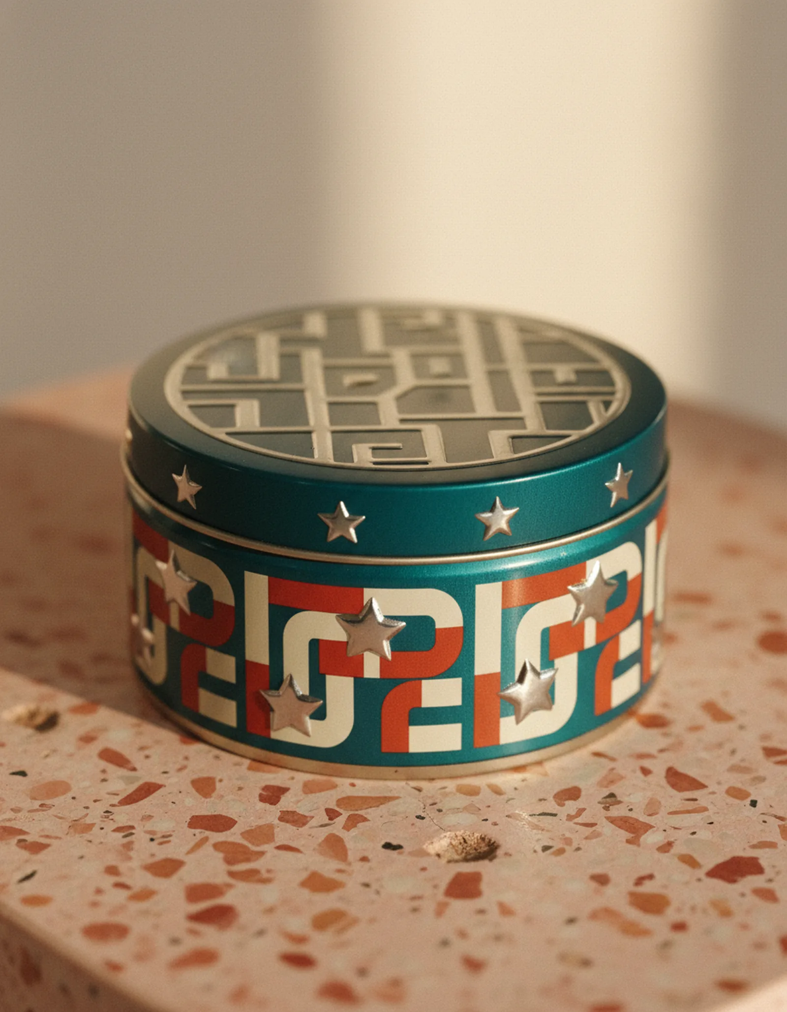 Round decorative tin with retro-futuristic graphic wrap and embossed lid on a terrazzo surface